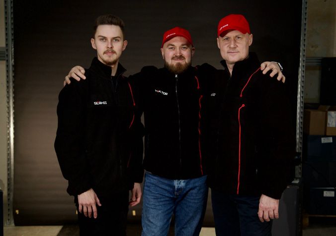 Three of the EHOSS team in branded jackets at the workshop door